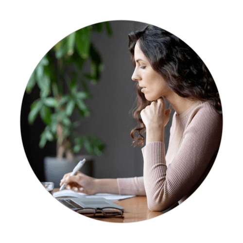 Woman thoughtfully writing notes at a desk, symbolizing end-of-life planning and reflection.