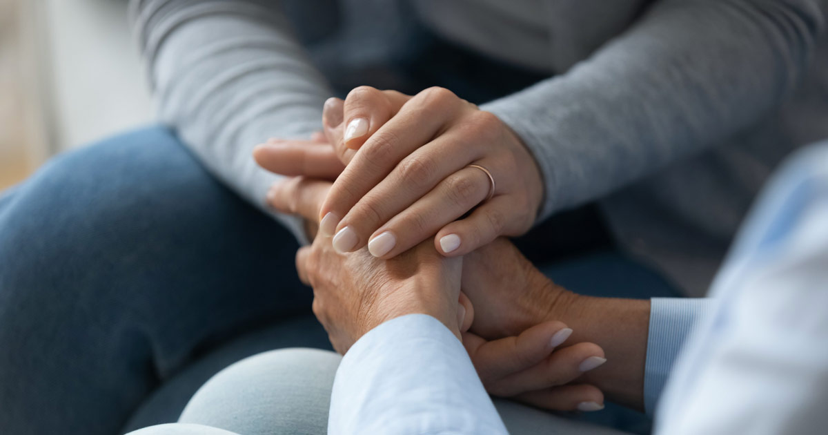 Gentle hands holding a client’s hand, homepage header for End-of-Life Doula care services, symbolizing compassion, comfort, and support.